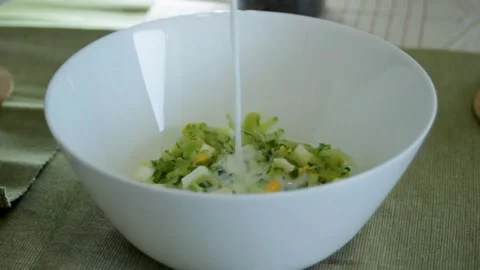 Summer soup Tarator close-up. Ayran pours into a plate of vegetables. Stock Footage 314996320