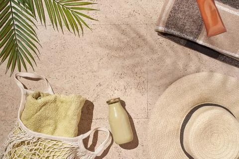 Summer sun beach concept flat lay.Hat, string bag with towel and bottle, leaves Stock Photos