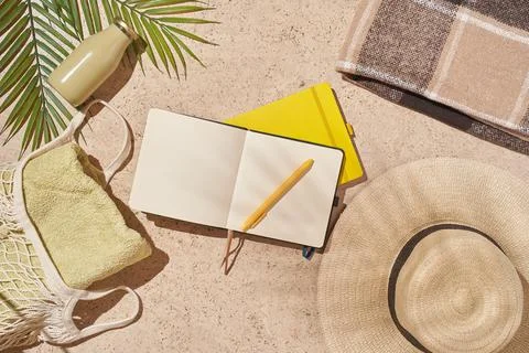 Summer sun beach concept flat lay.Hat, string bag with towel, notepad and leaves Stock Photos