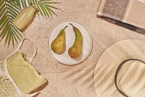 Summer sun beach concept flat lay.Hat, string bag with towel, pear, palm leaves. Stock Photos