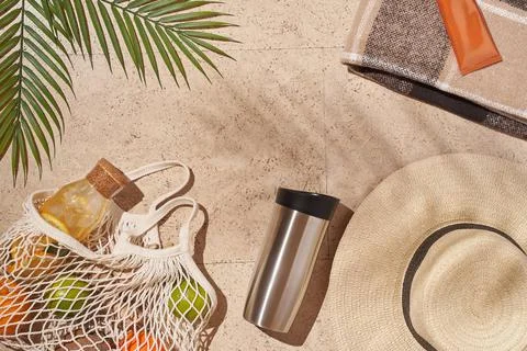 Summer sun beach concept flat lay.Hat, string bag with fruits, cup, palm leaves. Stock Photos