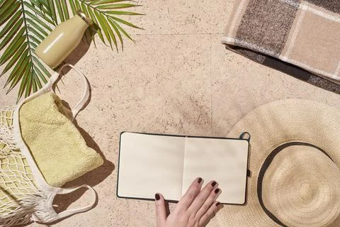 Summer sun beach concept flat lay. Hat, string bag, hand holding notepad. Stock Photos