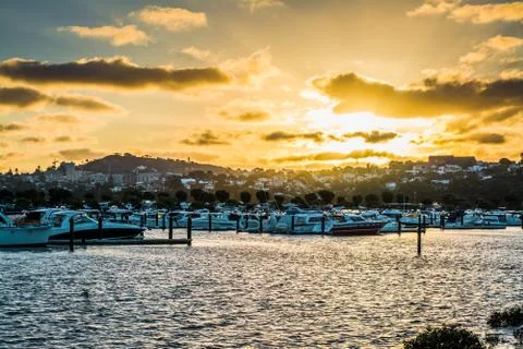 Summer sun setting into clouds over marina Stock Photos