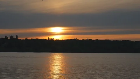 Summer sunset similar to a flash on the background of a calm river Stock Footage 117518056