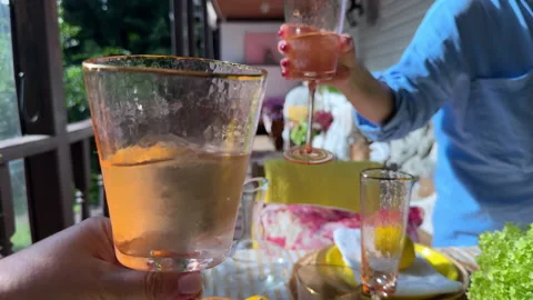 A summer table is set with lemons and flowers. A woman slices citrus, arranges h Stock Footage 312408424