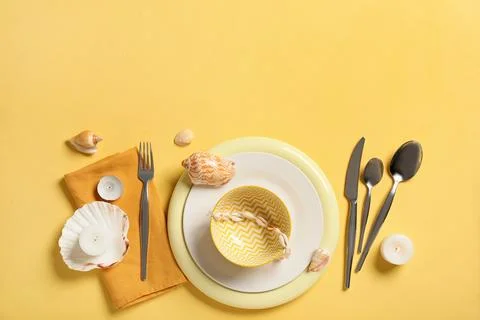 Summer table setting with seashells, candles, and yellow dinnerware on a brig Stock Photos