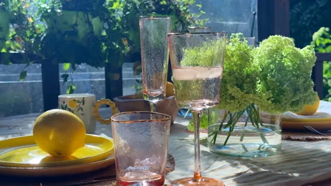 Summer table setting on a sunny veranda. Rustic yet elegant. A woman places ice  Stock Footage 312408427
