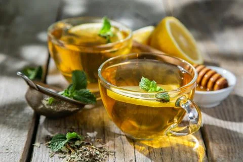 Summer tea - tea cups on rustic wood background with leaves shades - garden Stock Photos