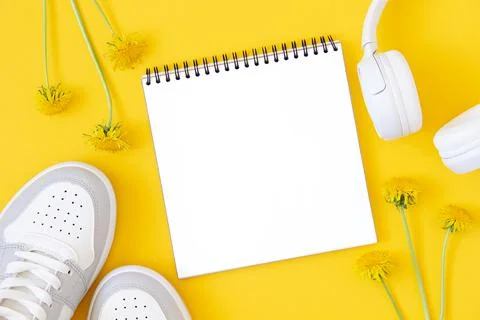 Summer template with white blank notebook, sneakers, headphones and flowers o Stock Photos