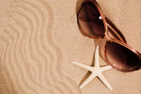 Summer textured background with waves of sand, sea star and pink sunglasses Stock-Fotos