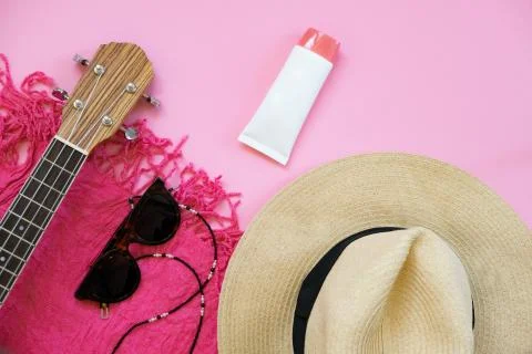 Summer things on a pink background. Straw hat, towel, ukulele and sunglasses. Stock Photos