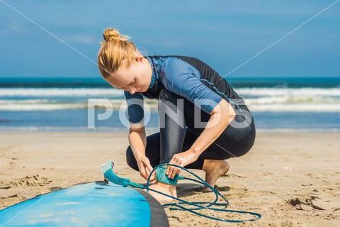 Summer time and active rest concept. Young surfer woman beginner fastens leash Stock Photos