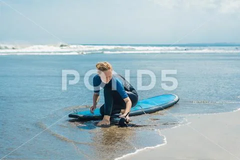 Summer time and active rest concept. Young surfer woman beginner fastens leash Stock Photos
