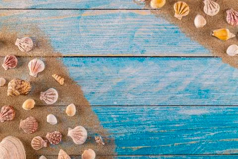 Summer time concept with sea shells on a blue wooden background and sand Stockfoto's