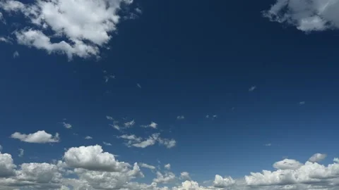 Summer timelapse of fluffy white clouds moving through a richly blue colored sky Stock Footage 312076532