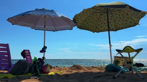 Summer vacation beach scene with open sun umbrellas and empty chairs and Stock Footage 218302834