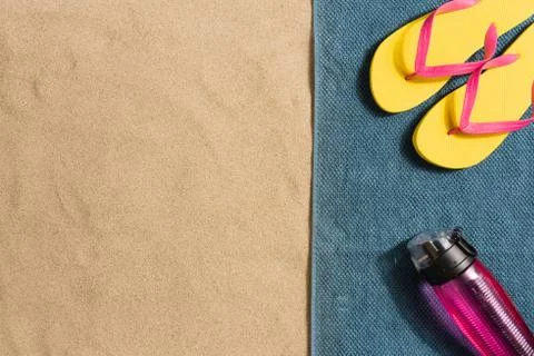 Summer vacation composition. Flip flops, bottle of water on sand background.  Stock Photos