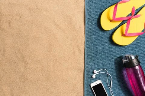 Summer vacation composition. Flip flops, smartphone and water bottle on sand  Stock Photos