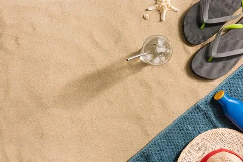 Summer vacation composition. Flip flops, hat, sun cream and glass of water on Stock Photos