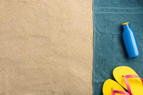 Summer vacation composition. Flip flops and sun cream on sand background. Har Stock Photos