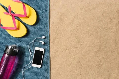 Summer vacation composition. Flip flops, smartphone and water bottle on sand  Stock Photos