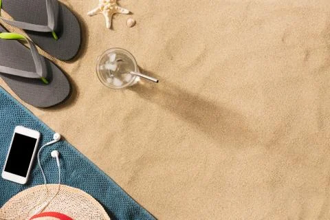 Summer vacation composition. Flip flops, hat, smartphone and glass of water o Stock Photos