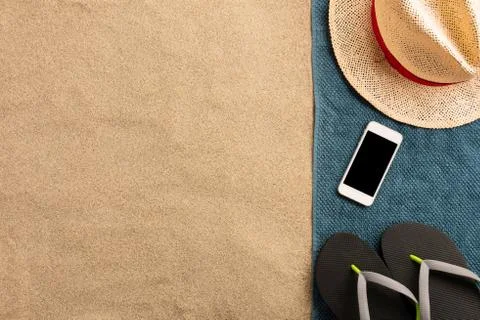 Summer vacation composition. Hat, smartphone and flip flops on sand. Harsh li Stock Photos