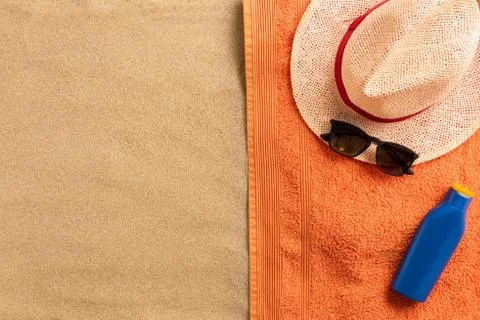 Summer vacation composition. Straw hat, sunglasses and sun cream on sand back Stock Photos