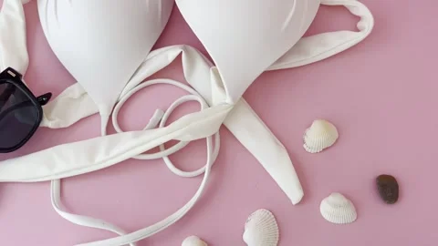 Summer vacation preparation with white bikini top, sunglasses, and seashell.. Vídeos de archivo 334617401