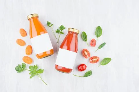 Summer vegetable juices of tomato and carrot in glass bottles with blank labe Stock Photos