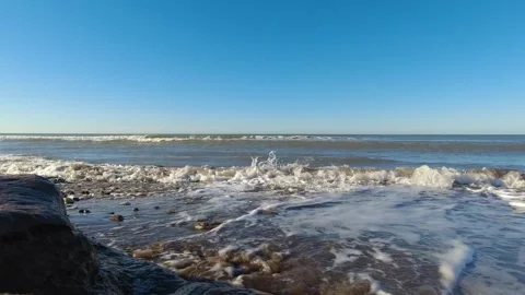 Summer: Waves breaking over the shoreline of a beach with rocks creating fo.. Stock Footage 272510995