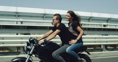 In the summer windy day young couple have a ride with a big black motorcycle in Stock Footage 102799997