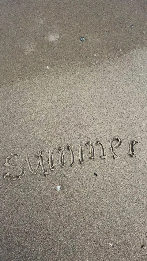 Summer written in sand by the seaside under sunlight Stock Footage 329319782