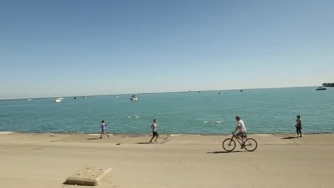Summertime at Chicago Beach featuring bikers, boaters, and swimmers Stock Footage 70792572