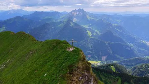 Summit cross overlooking alpine valley aerial drone view Photos