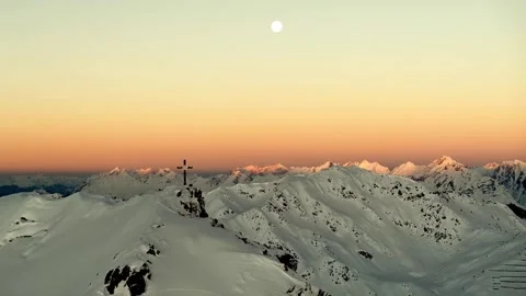 Summit cross on snowy mountain peak during golden sunset with moon. Stock-Footage 341068073