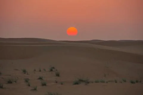 Sun almost touching the sand dunes Stock Photos