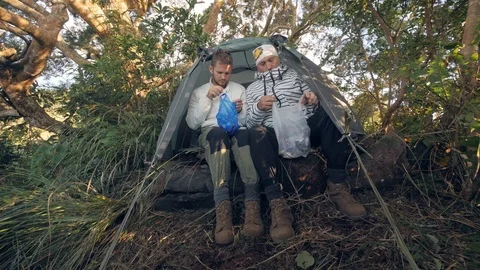 Sun and dad having breakfast in forest camp peeling boiled eggs in plastic bags. Stock Footage 118412914