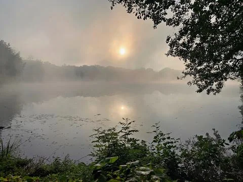 Sun and Mist Reflected on a Tranquil Lake at Autumn Dawn Foto stock