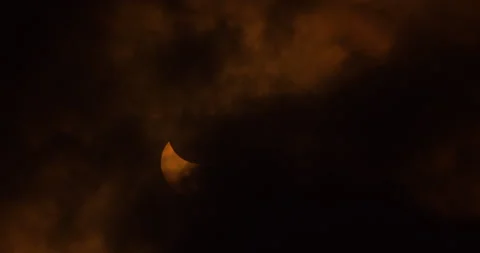 The sun and moon in a partial solar eclipse being obscured by clouds, Stock Footage 253372487