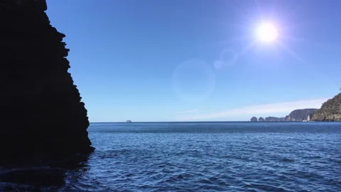 Sun and sea. Tracking past silhouette of rocky outcrop. Stock Footage 159316554