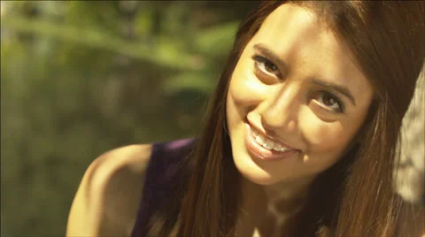 Sun and shadow dappled face of a beautiful girl outdoors by water Stock Footage 34438998