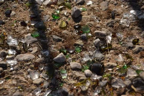 Sun and shadow falling on shattered glass and stones on dusty ground Stock Photos