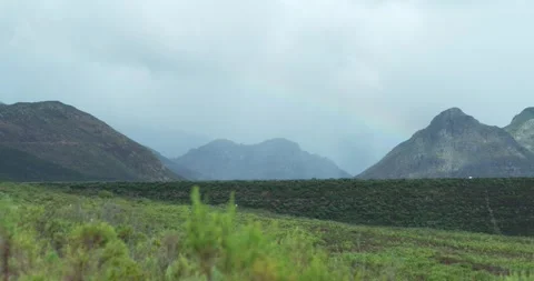 Sun and shadow passing over valley with small rainbow Stock Footage 277389998