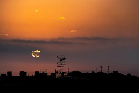 Sun appears from behind the clouds, above the city, roof top view. Stock Photos