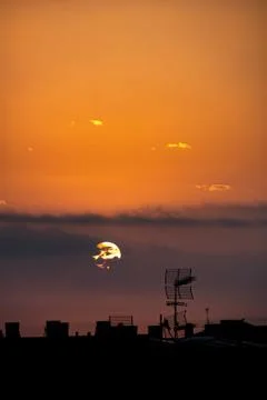 Sun appears from behind the clouds, above the city, roof top view. 스톡 사진