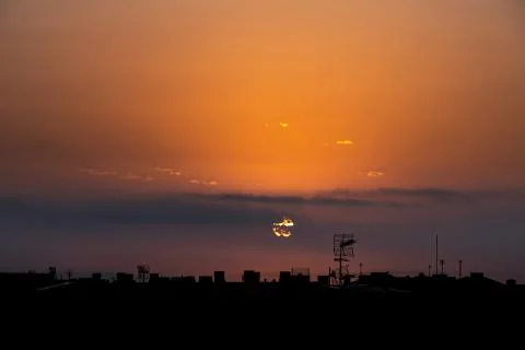 Sun appears from behind the clouds, above the city, roof top view. Фото