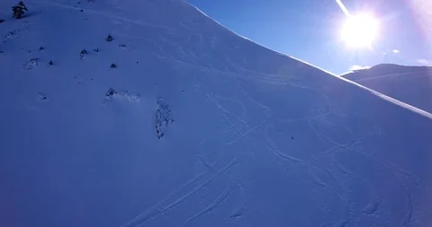 Sun appears over ski tracks and ridge on steep off piste slope Stock Footage 93455581