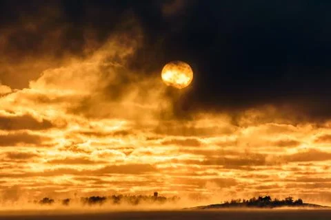Sun apppear through dark clouds above freezing Baltic Sea Stock Photos