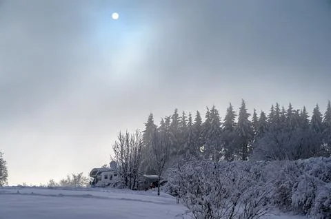 Sun barely visible through clouds in snow landscape with a mobile home or camper Stock Photos